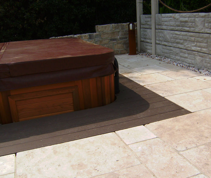 Installed hot tub with decked access well and travertine paving.