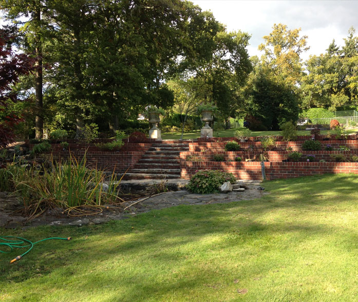 Raised brick bed landscaping with central steps and planting.