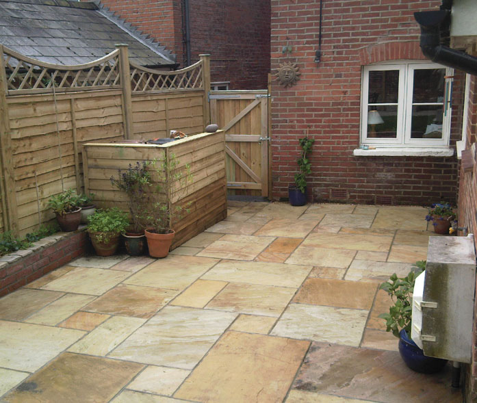 'Golden fossil' sandstone paving with wooden bin store.